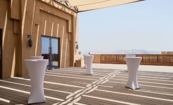 a rooftop patio with white tables and chairs set up for an outdoor event , possibly a wedding reception at Anantara Al Jabal Al Akhdar Resort