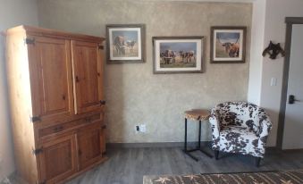 a living room with a wooden armoire , a chair , and three framed pictures on the wall at Rays Place Inn