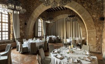 a large , elegant dining room with multiple round tables covered in white tablecloths and set for a formal event at Parador de Siguenza