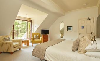 a large bed with a white comforter and yellow accent pillow is in the middle of a room with a mirror , chair , and window at Willowbeck Lodge Boutique Hotel