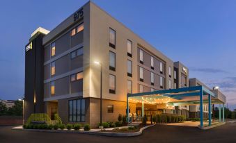 a holiday inn express hotel at night , with its exterior lit up and people walking in front of the entrance at Home2 Suites by Hilton Downingtown Exton Route 30