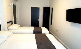 a hotel room with two beds , a flat - screen tv mounted on the wall , and a door at Wanstead Hotel