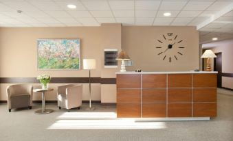 a modern hotel lobby with a reception desk , chairs , and a clock on the wall at L'Hotel