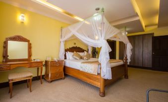 a large bed with a wooden headboard and canopy is in a room with yellow walls at Rainbow Ruiru Resort