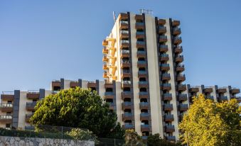 a tall apartment building surrounded by trees and grass , with a blue sky in the background at Hotel Estoril Eden