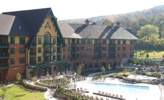 a large resort with multiple buildings , a pool , and surrounding trees , under a clear blue sky at The Appalachian at Mountain Creek