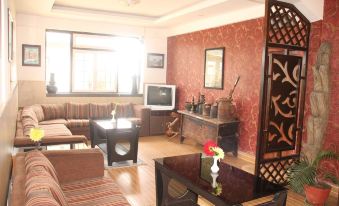 a cozy living room with a brown couch , a wooden coffee table , and a television at Hotel Srinagar