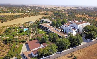 an aerial view of a large white building surrounded by trees and a body of water at Convento do Espinheiro, Historic Hotel & Spa