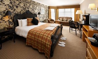 a hotel room with a king - sized bed , two chairs , and a couch , all decorated in a traditional style at Mercure Bristol North the Grange Hotel