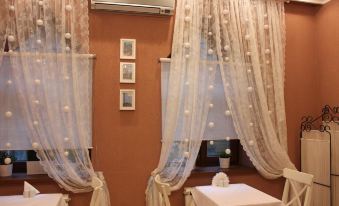 a room with white curtains , wooden furniture , and three framed pictures on the wall , as well as an air conditioner above the window at Serebryanyy Bor