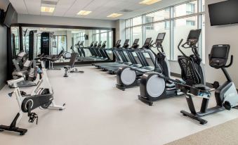a well - equipped gym with various exercise equipment , including treadmills and stationary bikes , arranged in rows at Hilton Vancouver Washington