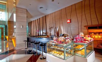 a modern bakery with a counter filled with various pastries and desserts , including cakes , donuts , and cupcakes at Grand Artos Hotel & Convention