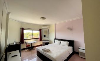 a large bed with white sheets is in a room with pink walls and a window at The Great Rayong Hotel