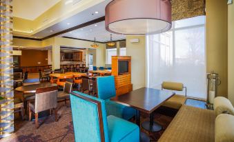 a large , well - lit room with multiple dining tables and chairs , as well as a television in the background at Hilton Garden Inn Kankakee