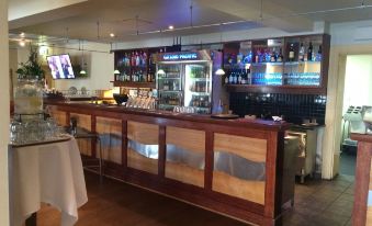 a bar with a wooden counter , wine glasses , and various bottles of alcohol on display at Grand Pacific Hotel