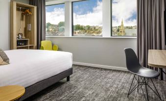 a hotel room with a large window overlooking the city , a bed , and a dining table at Mercure Newport