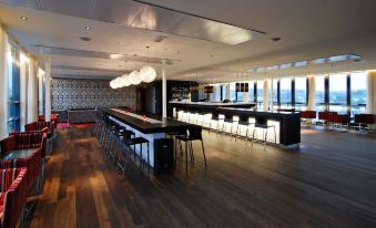 a modern bar area with wooden floors , a long counter , and several chairs surrounding it at Quality Hotel Fredrikstad