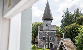 a traditional church with a pointed steeple and a clock tower , surrounded by lush green trees at Blue Pigeons