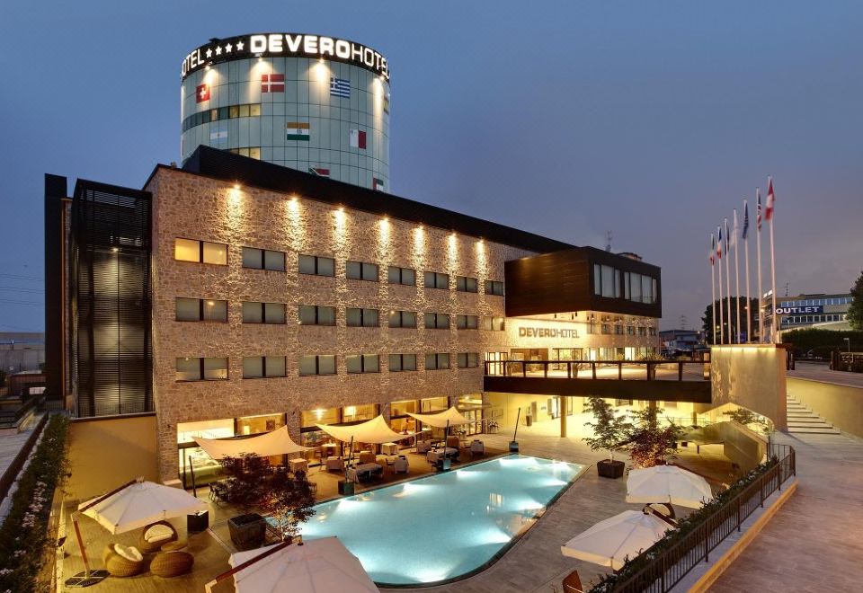 a large hotel with a swimming pool in the center , surrounded by tables and chairs at Devero Hotel  Spa, BW Signature Collection