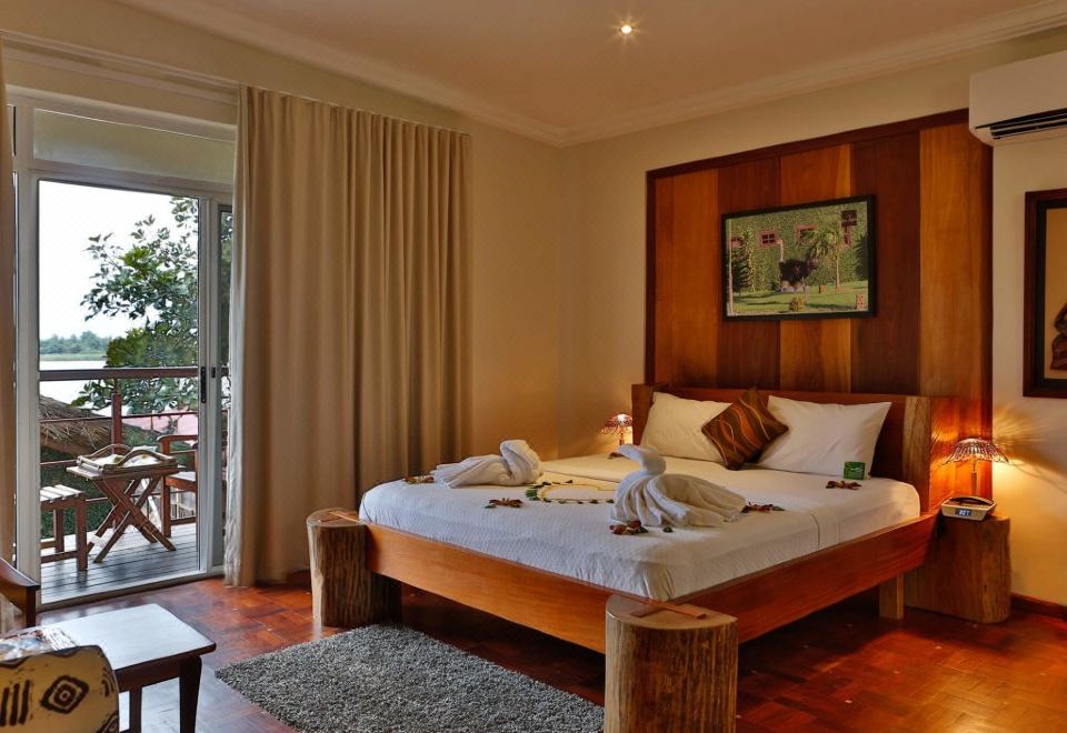 a well - decorated bedroom with a wooden bed , white linens , and a view of the outdoors at Aqua Safari Resort