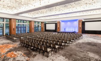 a large , empty conference room with rows of chairs and a projector screen at the front at Hilton Dallas Lincoln Centre