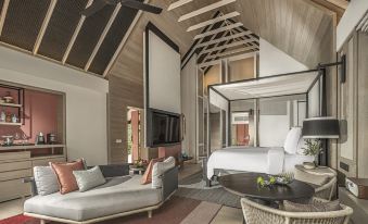 a modern hotel room with a large bed , couch , and dining table , all under a wooden ceiling at Four Seasons Resort Maldives at Landaa Giraavaru