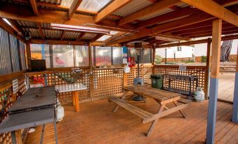 a wooden deck with a picnic table , grill , and trash can , surrounded by a corrugated metal roof at Discovery Parks - Hobart