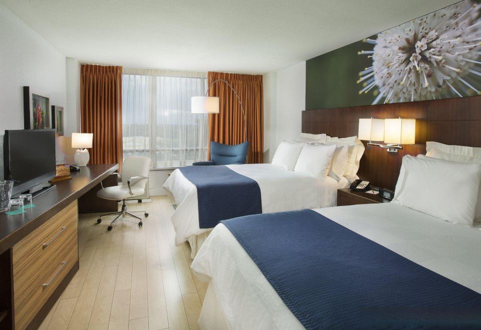 a hotel room with two beds , a desk , and a large window , all decorated in blue and white colors at Aloft Miami Dadeland