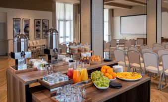 a dining area with a table filled with various food items , including fruits , juice , and other snacks at Doubletree by Hilton Brescia