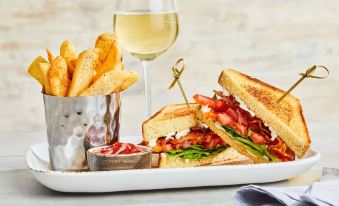 a white plate with a sandwich , french fries , and a glass of wine on a dining table at Courtyard Philadelphia Bensalem