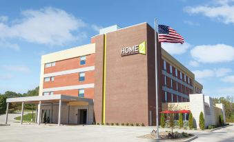 a large , modern hotel with a brown brick facade and an american flag flying above it at Home2 Suites by Hilton Canton