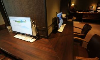a wooden desk with a computer and two monitors , one on each side of the desk at Mizno Hotel
