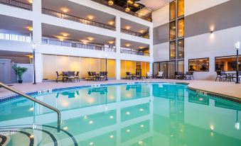 an indoor swimming pool in a hotel , surrounded by chairs and tables , with large windows providing natural light at Holiday Inn Morgantown - Reading Area