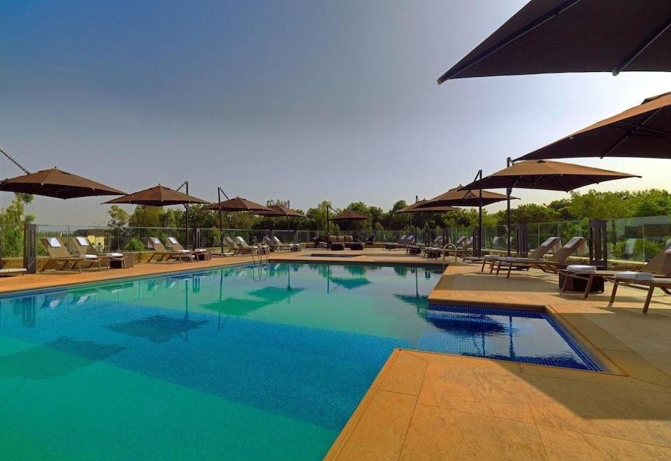 a large outdoor swimming pool surrounded by lounge chairs and umbrellas , providing a relaxing atmosphere at Radisson Blu Hotel, Bamako