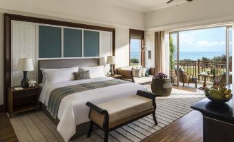 a large bedroom with a bed , nightstands , and a balcony view of the ocean , accompanied by chairs and a table at Shangri-La's Hambantota Golf Resort and Spa, Sri Lanka