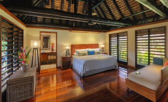 a spacious bedroom with hardwood floors , a large bed , and a television mounted on the wall at Jean-Michel Cousteau Resort Fiji