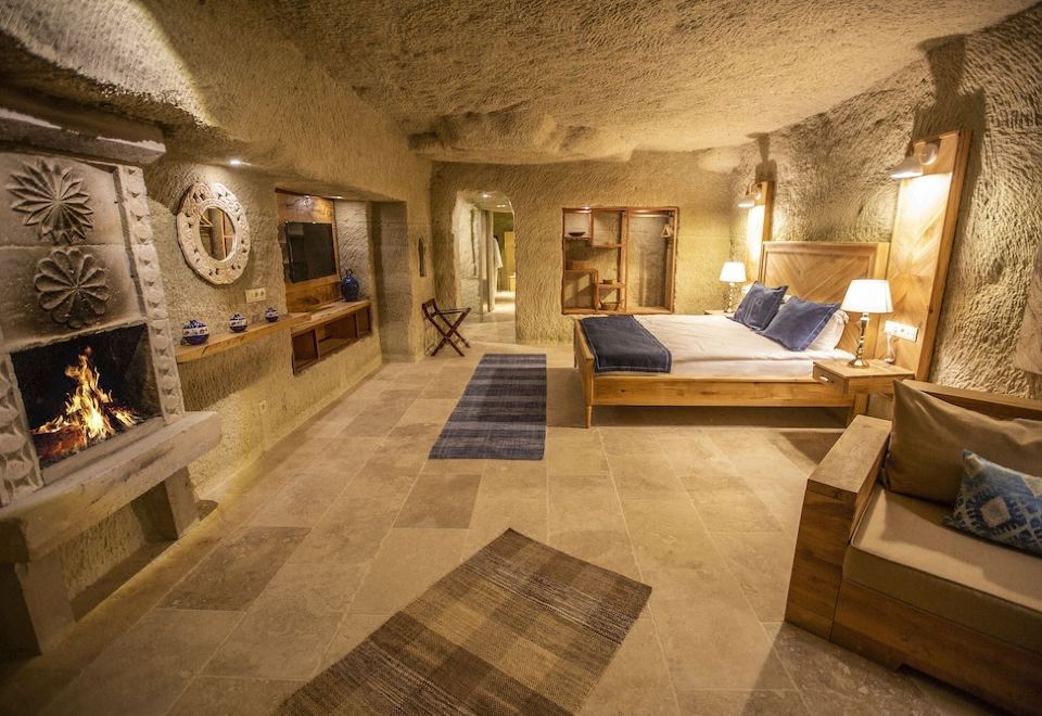 a luxurious bedroom with a king - sized bed , a bathroom , and a balcony overlooking the ocean at Azure Cave Suites - Cappadocia