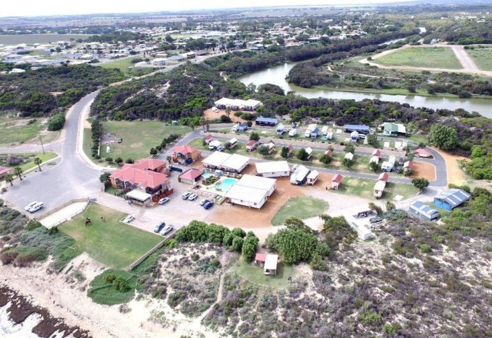a bird 's eye view of a residential area with houses , trees , and a river in the background at Seaspray Beach Holiday Park