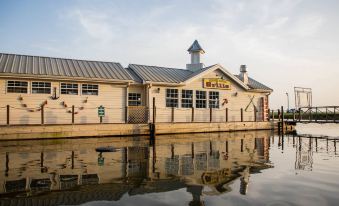 a restaurant with a tall clock tower is reflected in the water , casting reflections on the surface at Holiday Inn Club Vacations Villages Resort Lake Palestine