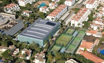 aerial view of a large building with a tennis court in front of it , surrounded by houses and roads at Estival Park Silmar