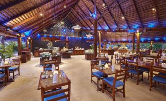 a large dining room with wooden tables and chairs arranged for a group of people to enjoy a meal together at Kuredu Island Resort & Spa