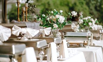 a dining table set with white chairs , wine glasses , and a vase of flowers , creating a elegant atmosphere at Bicentennial Inn