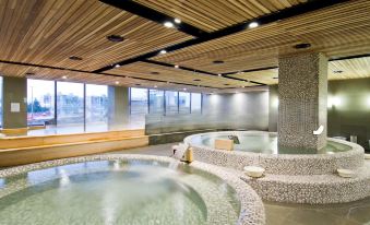a large indoor pool with multiple hot tubs , surrounded by wooden walls and a stone floor at The Riverside Hotel