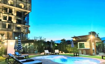 a modern apartment building with a large swimming pool and lounge chairs in front of it at Hotel Fuse Rayong