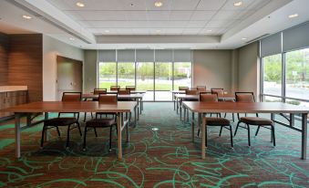 a conference room with wooden tables and chairs , a green carpet , and large windows offering views of the outdoors at Home2 Suites by Hilton Walpole Foxboro