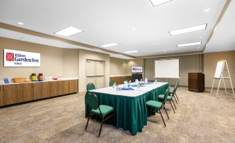 a conference room with a long table covered in a green tablecloth , chairs , and chairs arranged around them at Hilton Garden Inn Gilroy