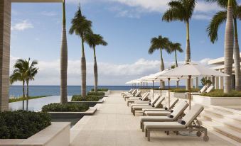 a row of sun loungers and umbrellas are lined up on a patio overlooking the ocean at Four Seasons Resort and Residence Anguilla