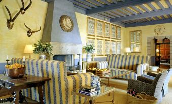 a cozy living room with blue and yellow striped furniture , a fireplace , and a deer head mounted on the wall at Parador de Jarandilla
