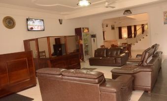 a living room with brown leather couches , a television , and a staircase leading to the second floor at Ibisa Hotel