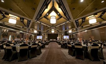a large banquet hall with multiple tables and chairs , and a stage in the background at Mercure Sydney Bankstown